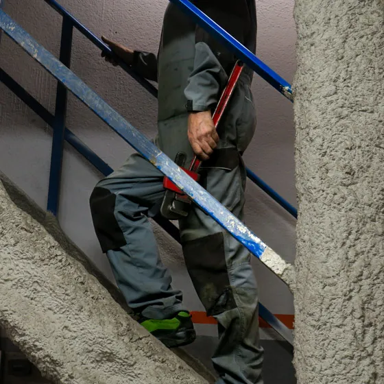 Operario con herramienta subiendo escalera